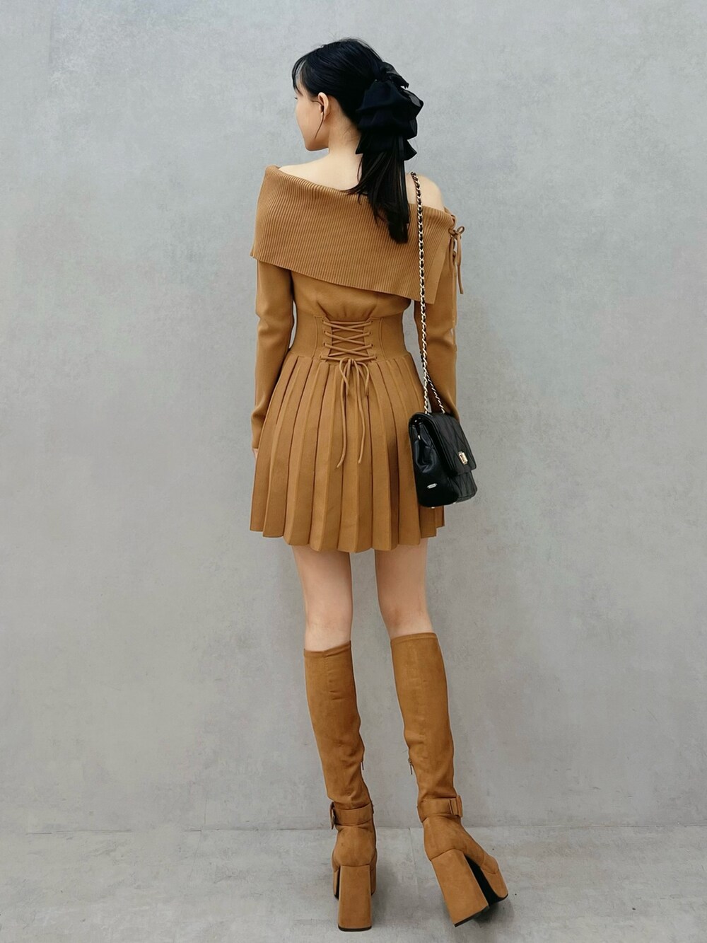 ブラウン系のワンピース、ブラウン系のブーツ、ブラック系のハンドバッグを着用したレディースの秋コーディネートの3枚目の写真