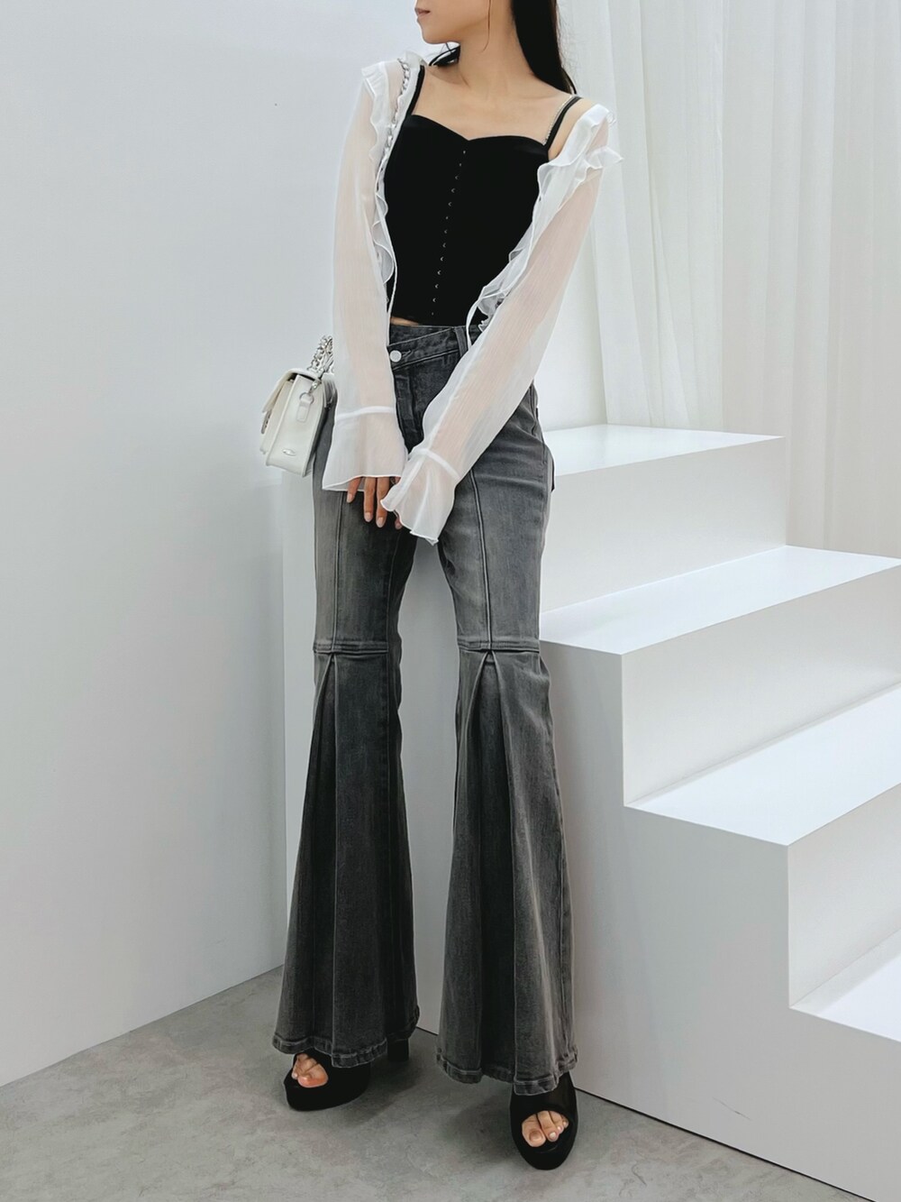 ブラック系のデニムパンツ、ブラック系のキャミソール、ホワイト系のカーディガン/ボレロを着用したレディースの秋コーディネートの7枚目の写真