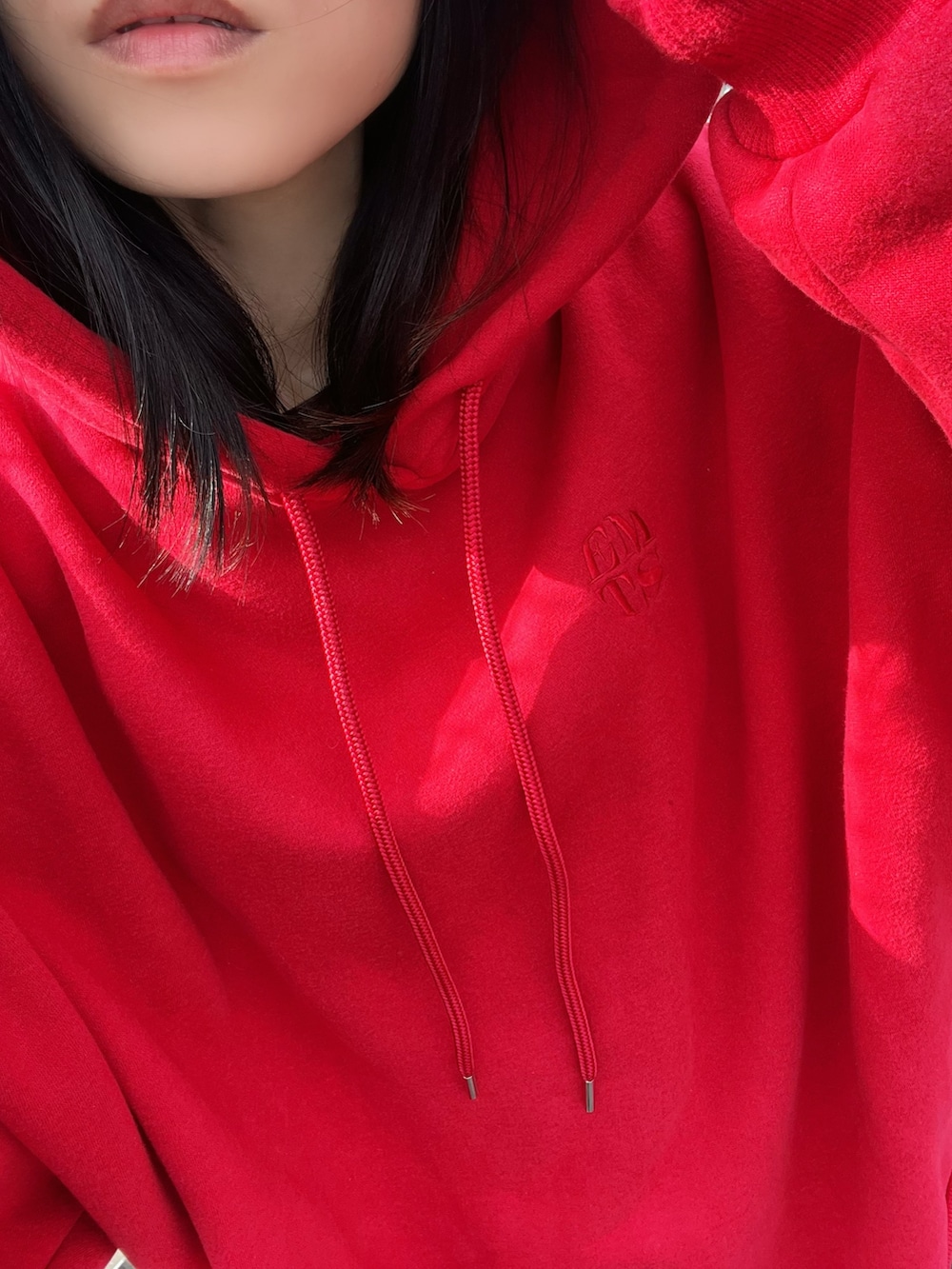 レッド系のパーカー、ブルー系のデニムパンツを着用したレディースの冬コーディネートの4枚目の写真