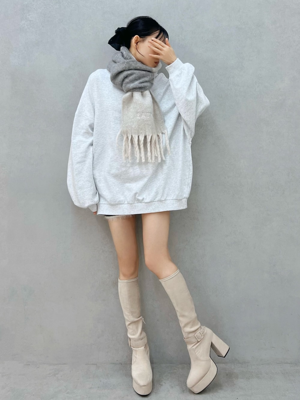 グレー系のスウェット、ホワイト系のブーツ、グレー系のマフラーを着用したレディースの秋コーディネートの2枚目の写真