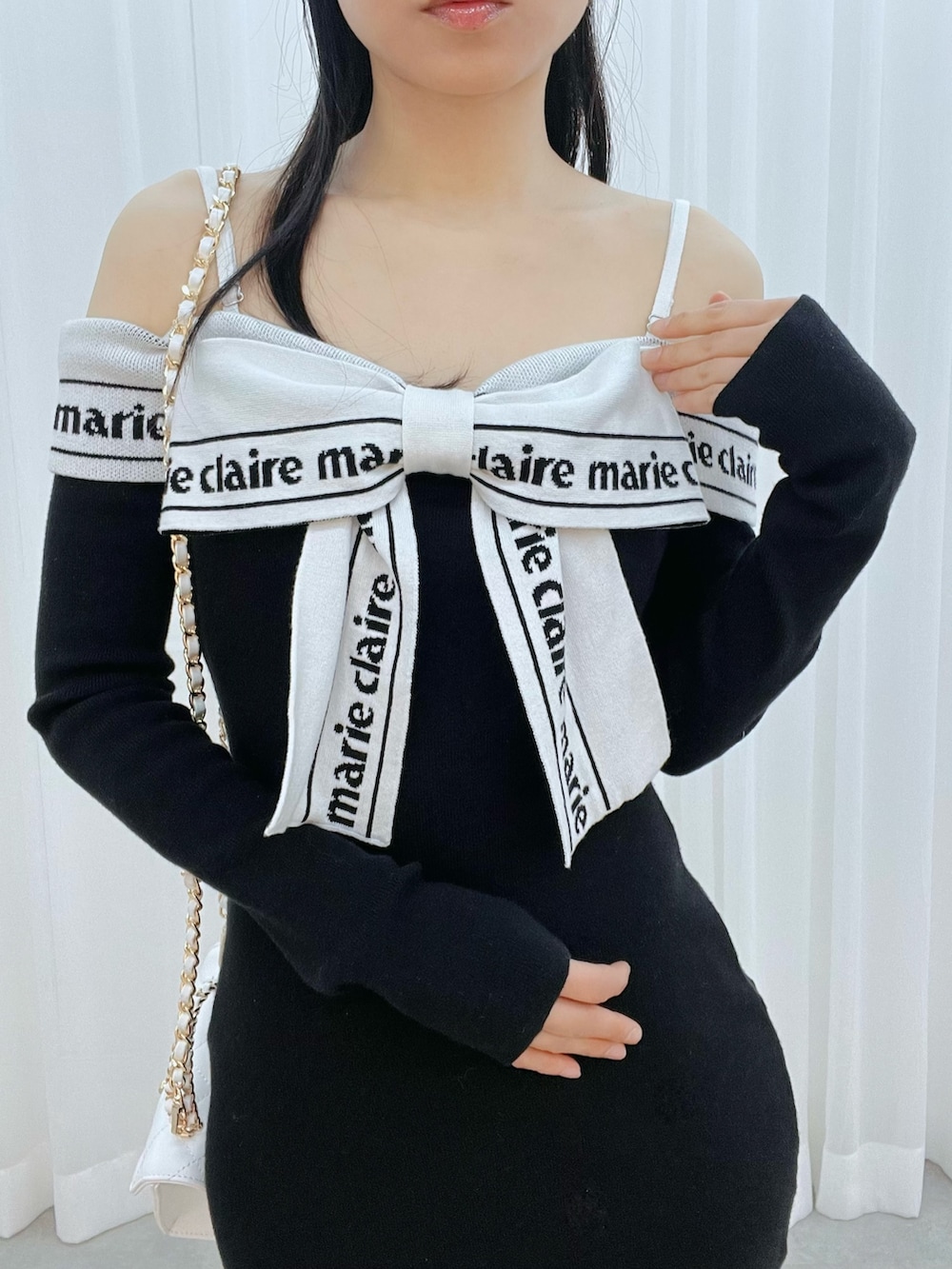 ホワイト系のブーツ、ホワイト系のハンドバッグ、ブラック系のワンピースを着用したレディースの冬コーディネートの4枚目の写真