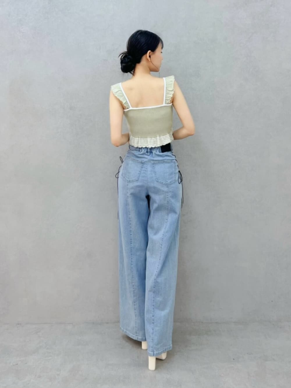 ホワイト系のサンダル、ブルー系のデニムパンツ、グリーン系のキャミソールを着用したレディースの夏コーディネートの3枚目の写真