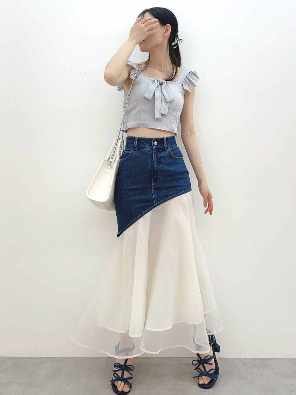 ブルー系のデニムスカート、ホワイト系のハンドバッグ、グレー系のシャツ/ブラウスを着用したレディースの春コーディネートの2枚目の写真