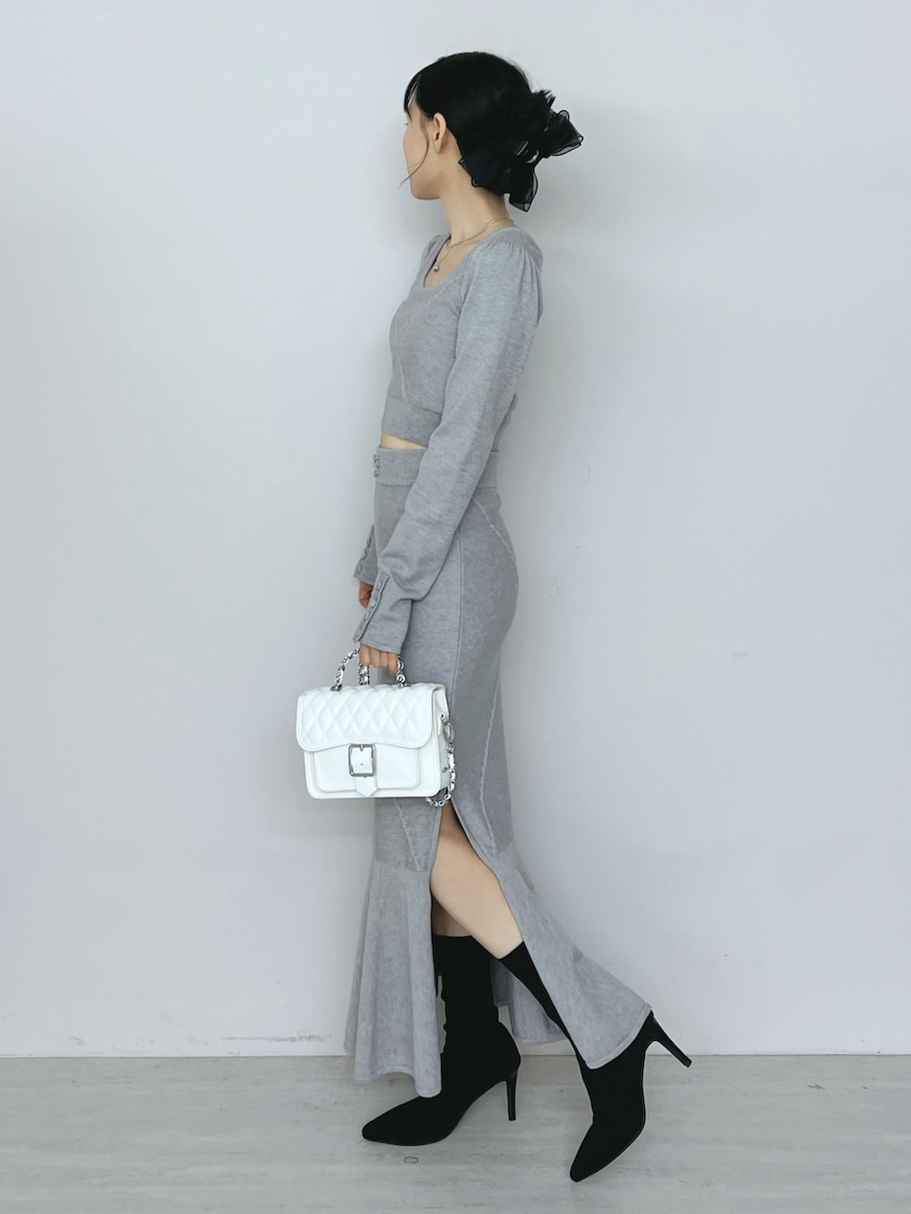 ホワイト系のショルダーバッグ、グレー系のニット/セーター、グレー系のスカートを着用したレディースの秋コーディネートの2枚目の写真