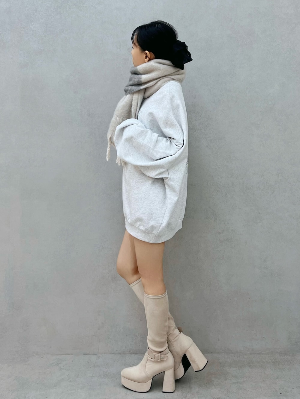 グレー系のスウェット、ホワイト系のブーツ、グレー系のマフラーを着用したレディースの秋コーディネートの3枚目の写真