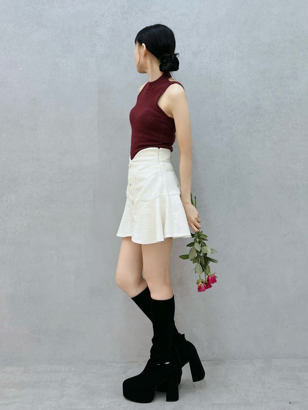 レッド系のニット/セーター、ホワイト系のスカート、ブラック系のブーツを着用したレディースの秋コーディネートの2枚目の写真