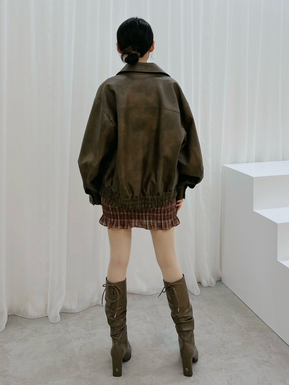 レッド系のワンピース、ブラウン系のブルゾン、ブラウン系のブーツを着用したレディースの秋コーディネートの3枚目の写真