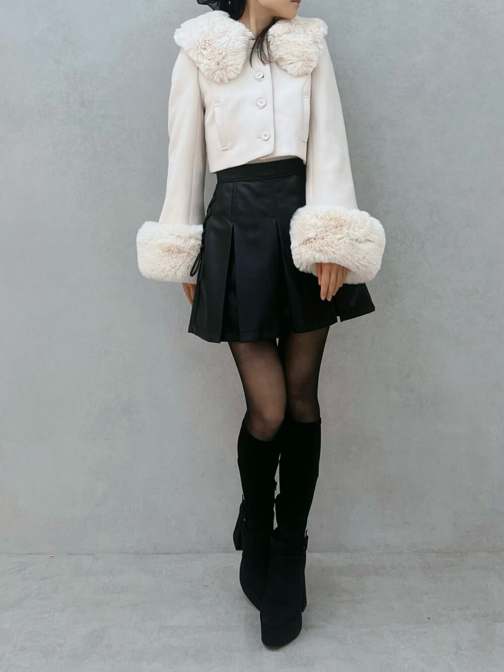 ブラック系のスカート、ホワイト系のその他アウター、ブラック系のブーツを着用したレディースの秋コーディネートの5枚目の写真