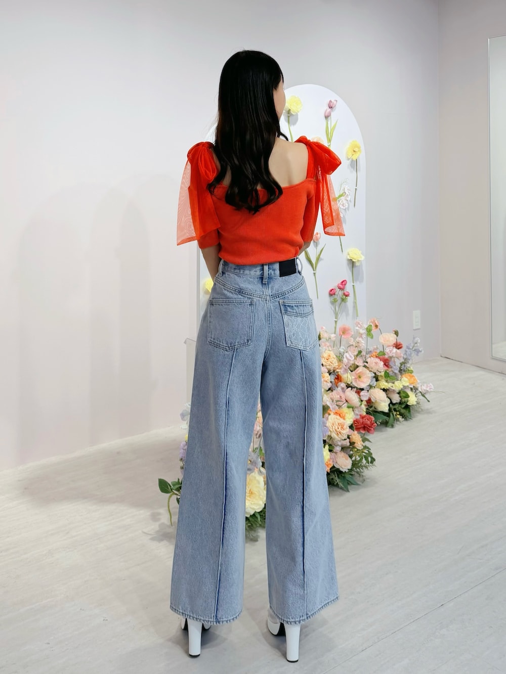 ブルー系のデニムパンツ、オレンジ系のTシャツ/カットソー、ホワイト系のブーツを着用したレディースの春コーディネートの3枚目の写真