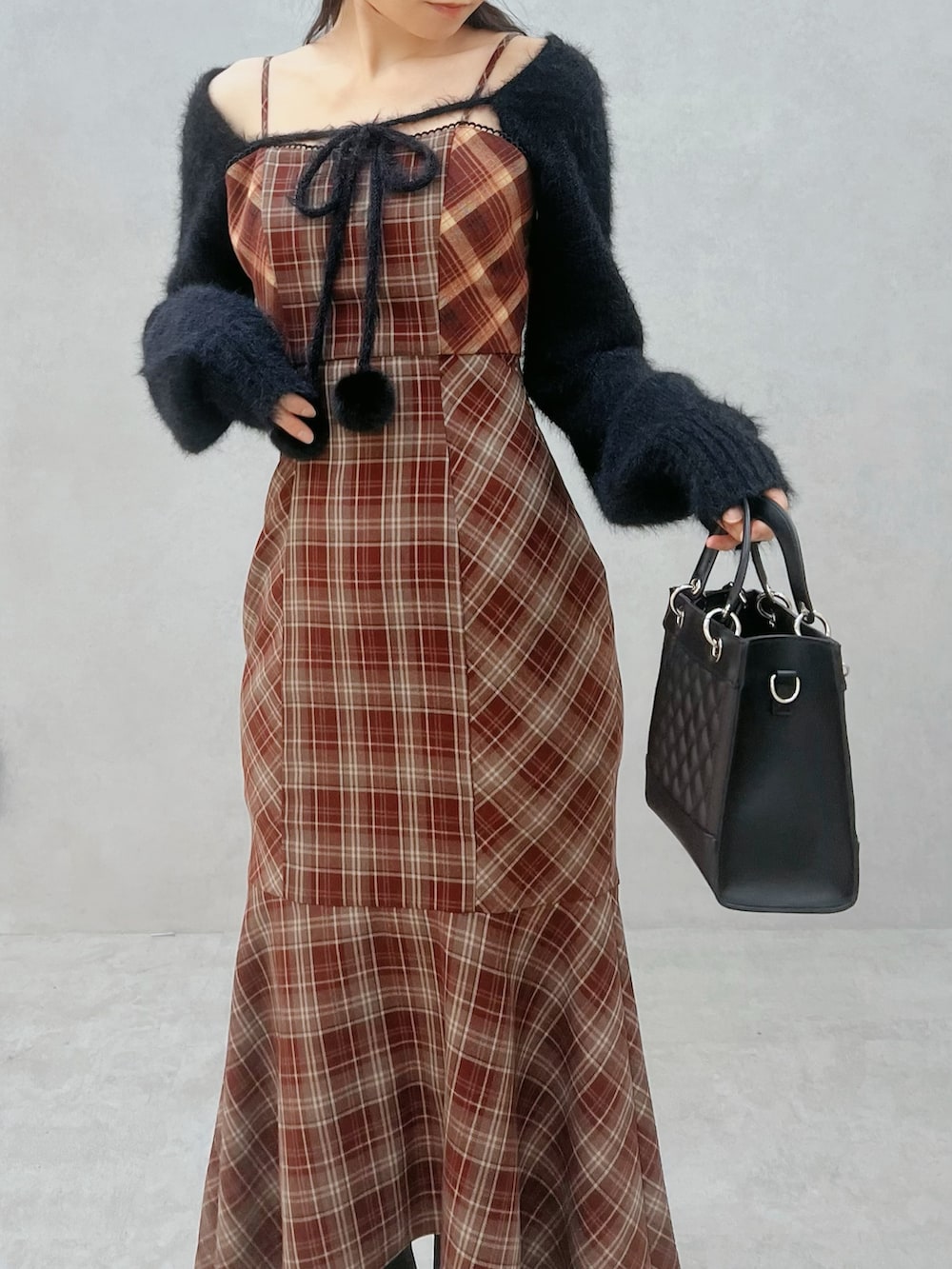 レッド系のワンピース、ブラック系のニット/セーター、ブラック系のブーツを着用したレディースの秋コーディネートの5枚目の写真