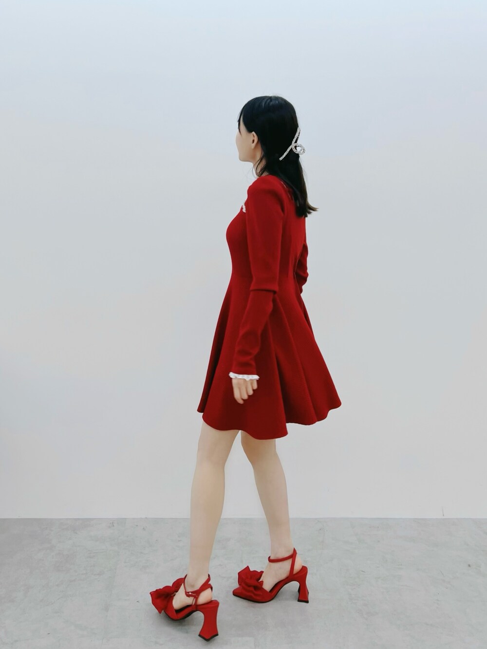 レッド系のワンピース、レッド系のパンプス、ブラック系のキャミソールを着用したレディースの冬コーディネートの3枚目の写真