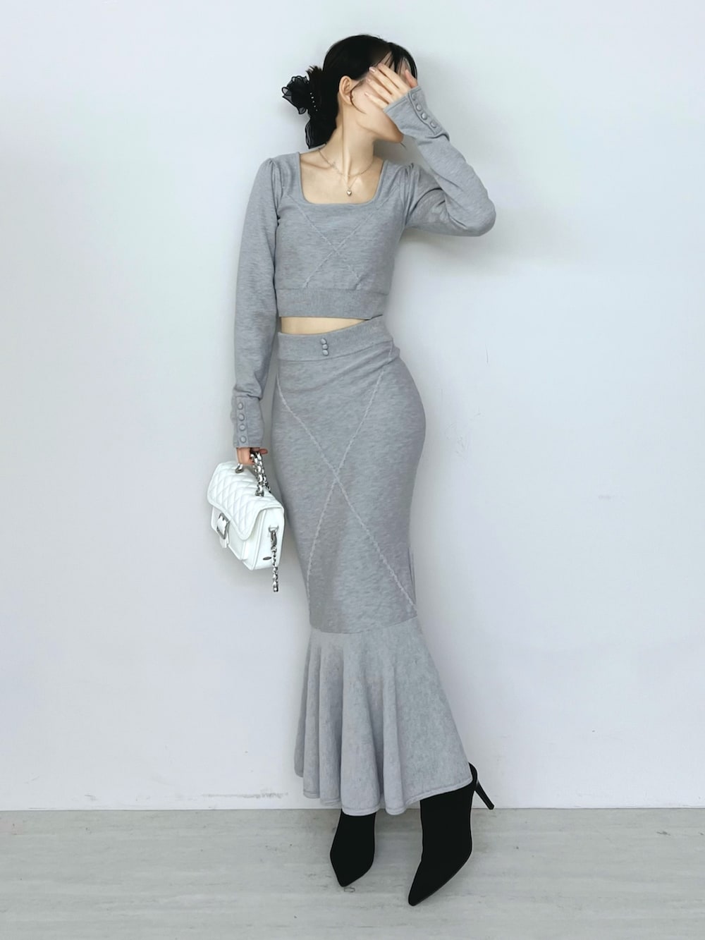 ホワイト系のショルダーバッグ、グレー系のニット/セーター、グレー系のスカートを着用したレディースの秋コーディネートの4枚目の写真