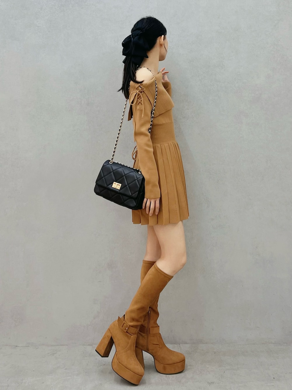 ブラウン系のワンピース、ブラウン系のブーツ、ブラック系のハンドバッグを着用したレディースの秋コーディネートの2枚目の写真
