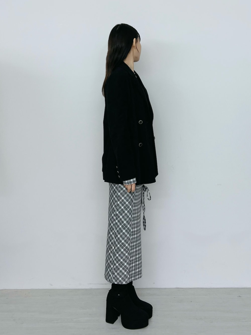 グレー系のワンピース、ブラック系のテーラードジャケット、ブラック系のブーツを着用したレディースの秋コーディネートの2枚目の写真