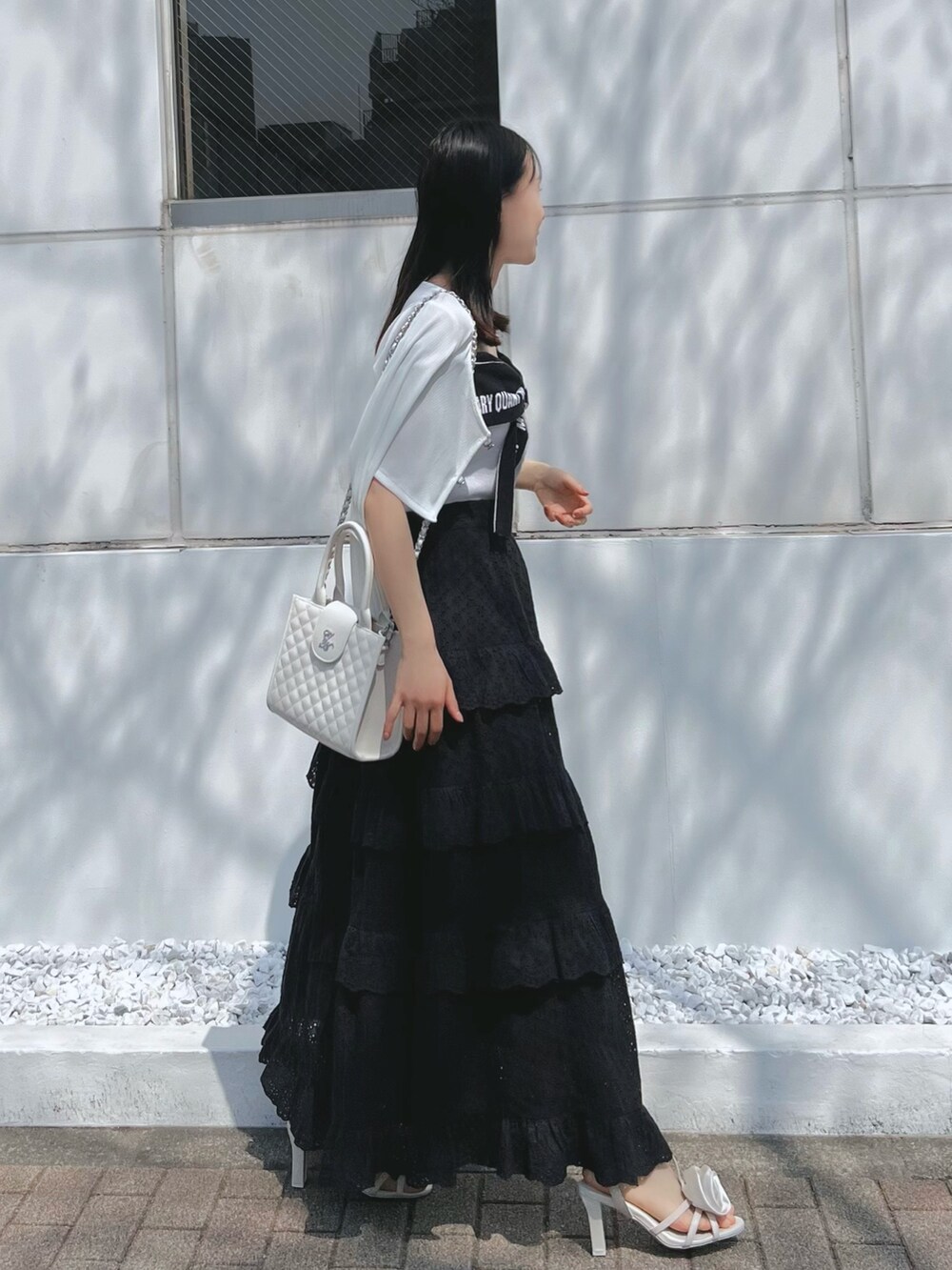 ブラック系のスカート、ホワイト系のワンピース、ホワイト系のサンダルを着用したレディースの春コーディネートの5枚目の写真