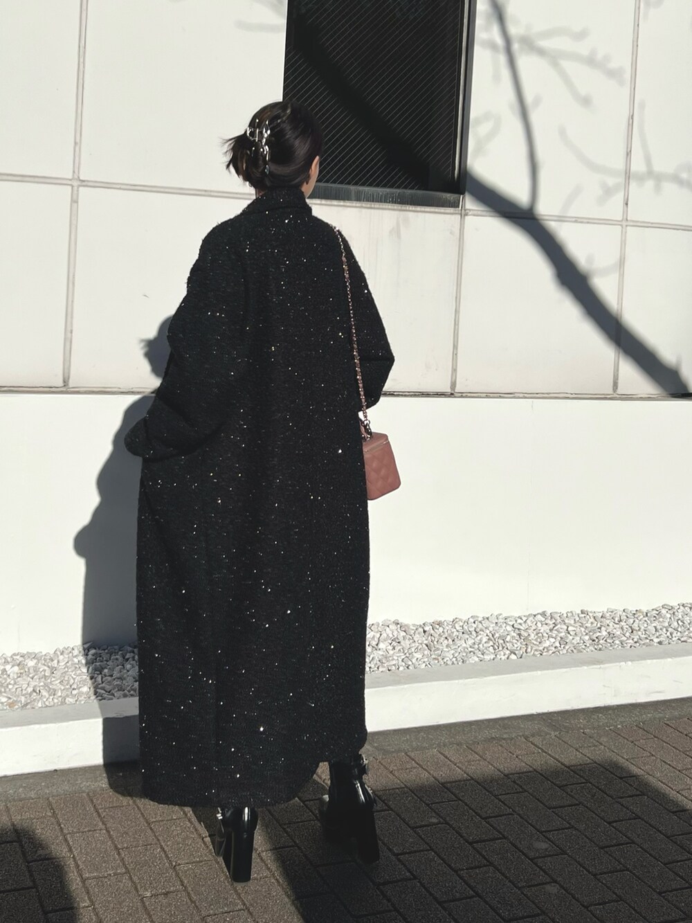 ピンク系のハンドバッグ、ブラック系のチェスターコート、ブラック系のブーツを着用したレディースの冬コーディネートの3枚目の写真