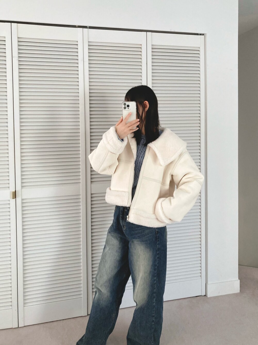 ホワイト系のブルゾン、ブルー系のデニムパンツを着用したレディースの冬コーディネートの4枚目の写真