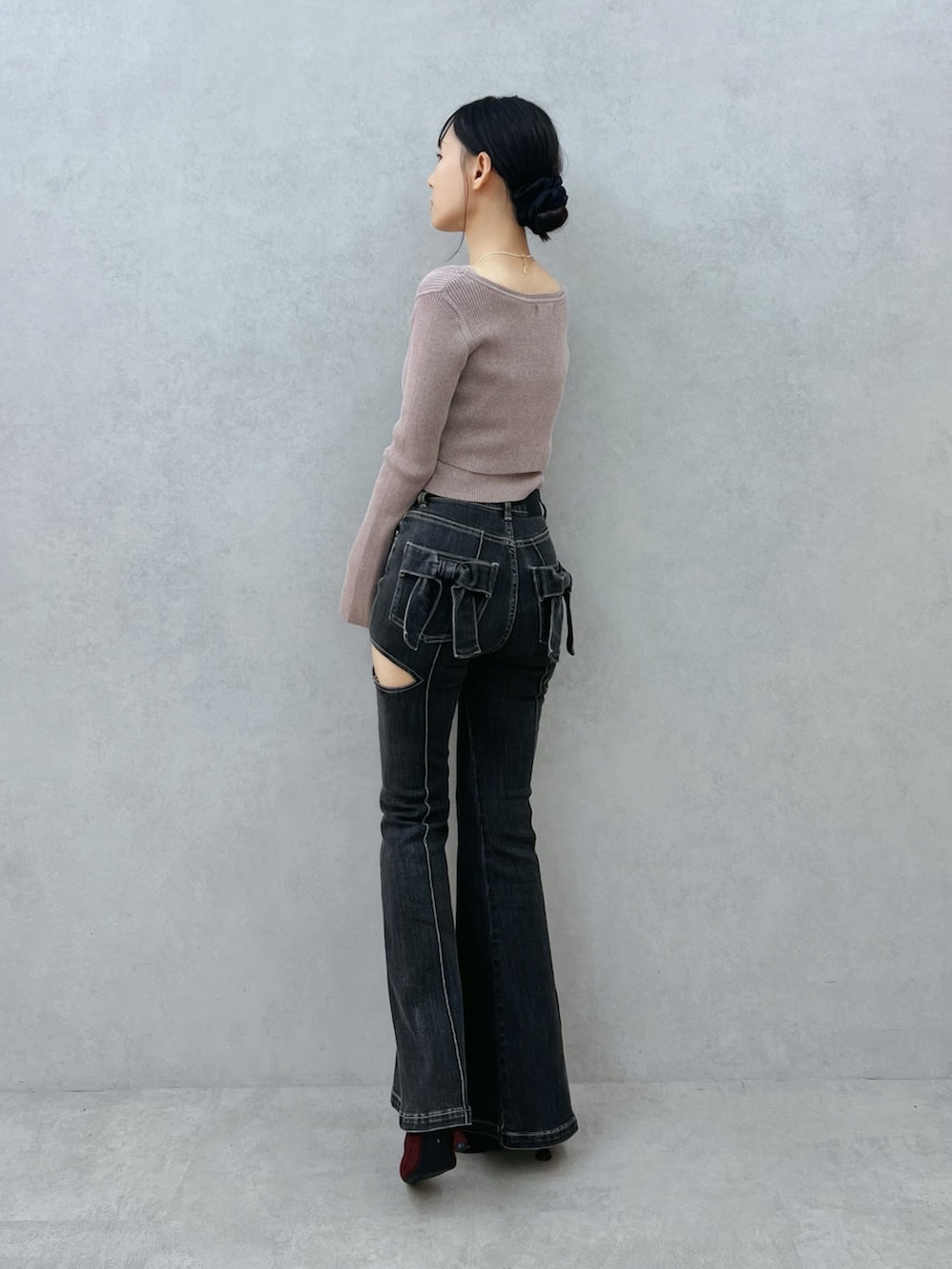 ブラック系のデニムパンツ、レッド系のブーツ、ベージュ系のニット/セーターを着用したレディースの夏コーディネートの4枚目の写真