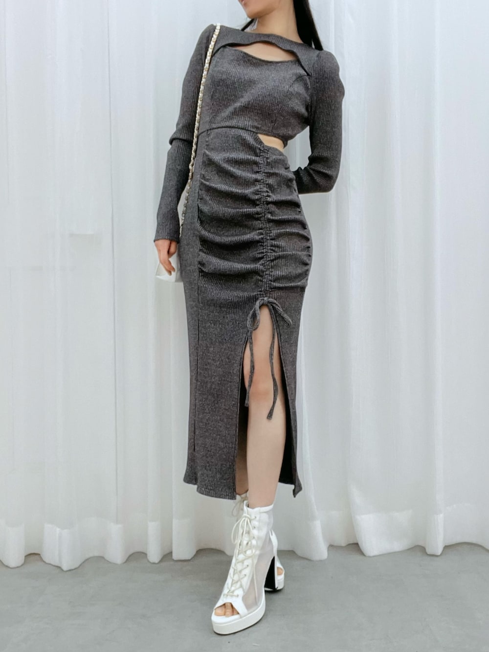 グレー系のワンピース、ホワイト系のブーツ、ホワイト系のハンドバッグを着用したレディースの冬コーディネートの4枚目の写真