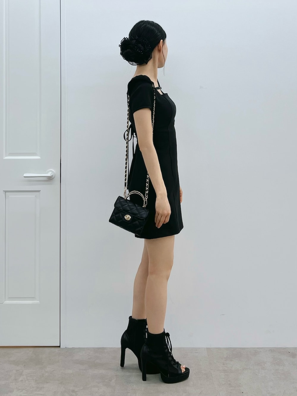 ブラック系のワンピース、ブラック系のブーツ、ブラック系のハンドバッグを着用したレディースの春コーディネートの2枚目の写真