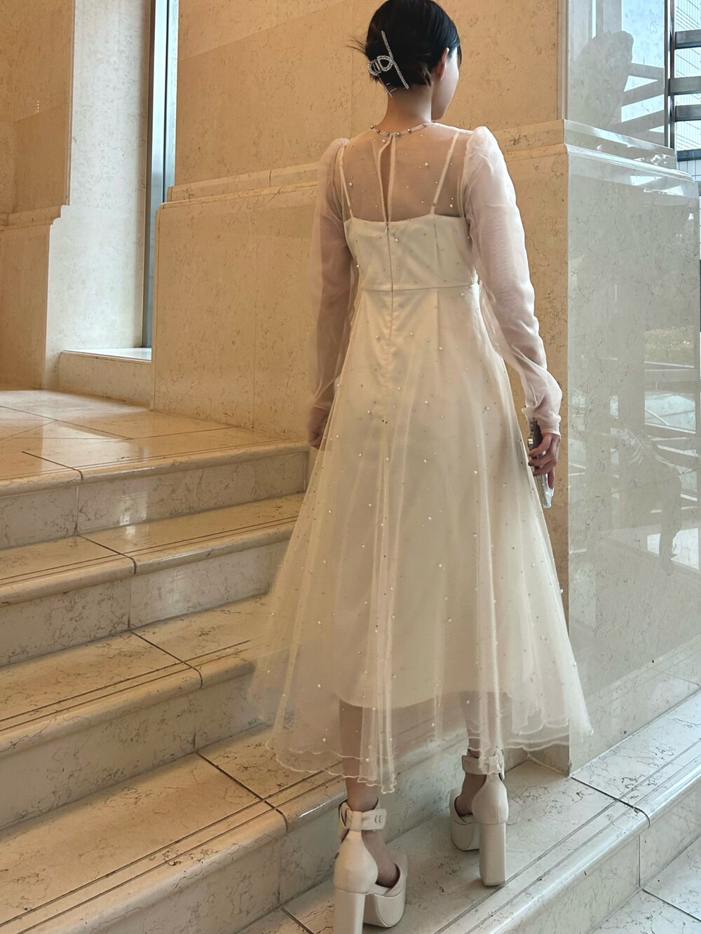 ホワイト系のワンピース、ホワイト系のパンプスを着用したレディースの冬コーディネートの4枚目の写真