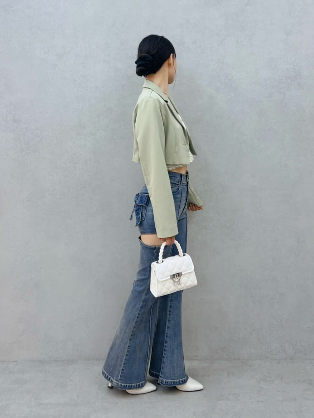 ブルー系のデニムパンツ、ホワイト系のハンドバッグ、ホワイト系のブーツを着用したレディースの秋コーディネートの2枚目の写真