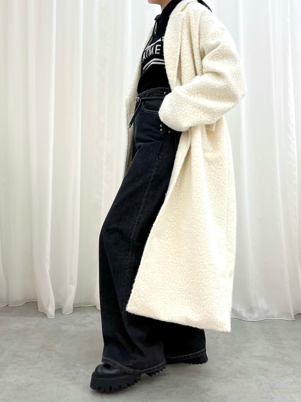 ブラック系のデニムパンツ、ホワイト系のチェスターコート、ブラック系のワンピースを着用したレディースの冬コーディネートの5枚目の写真