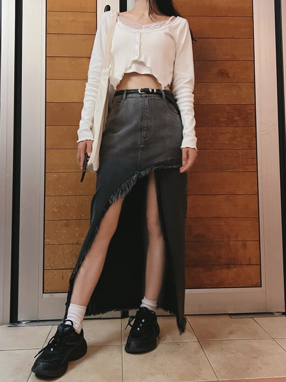 ブラック系のデニムスカート、ホワイト系のTシャツ/カットソーを着用したレディースの夏コーディネートの3枚目の写真