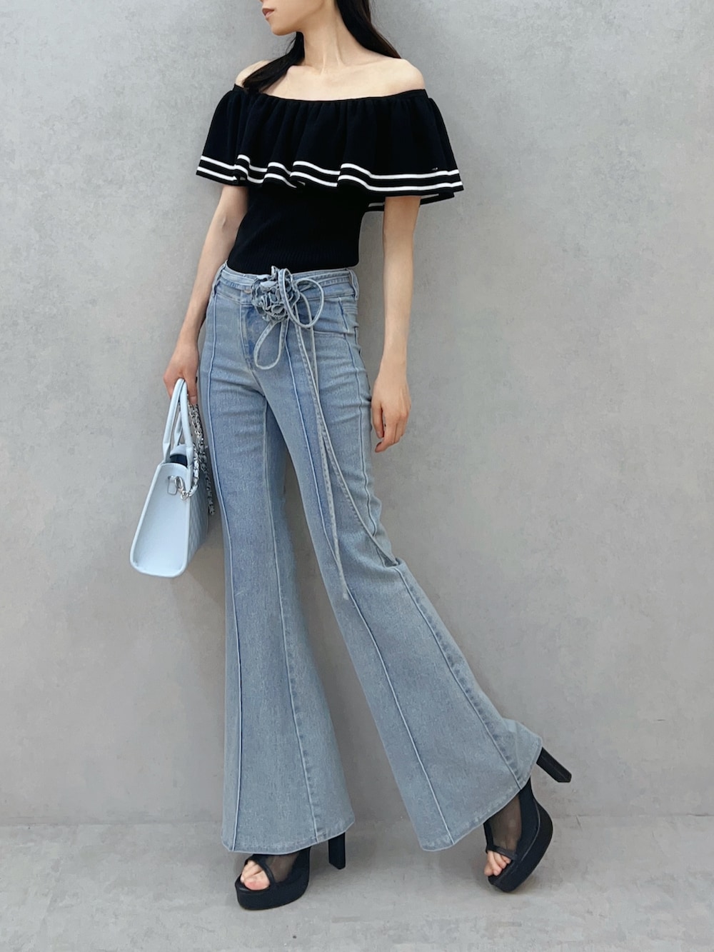 ブルー系のハンドバッグ、ブルー系のデニムパンツ、ブラック系のニット/セーターを着用したレディースの夏コーディネートの3枚目の写真