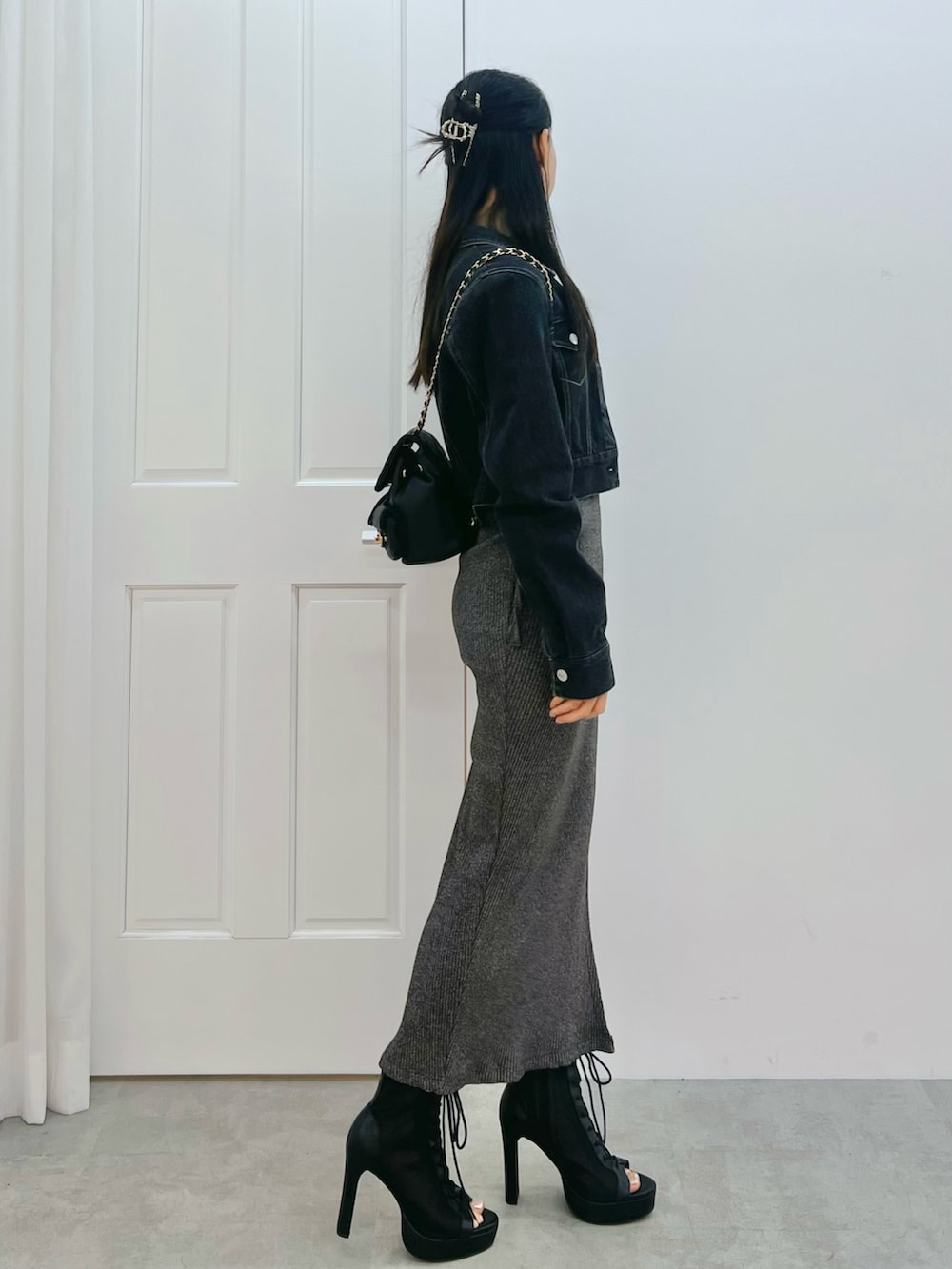 グレー系のワンピース、ブラック系のブーツ、ブラック系のデニムジャケットを着用したレディースの春コーディネートの2枚目の写真