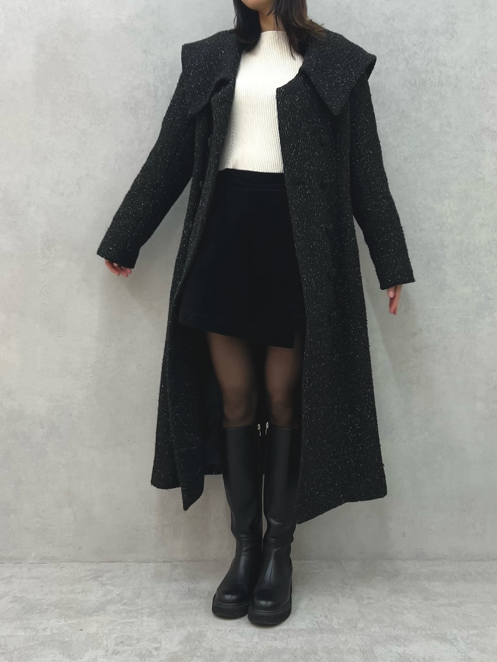 ブラック系のチェスターコート、レッド系のショルダーバッグ、ホワイト系のニット/セーターを着用したレディースの冬コーディネートの5枚目の写真