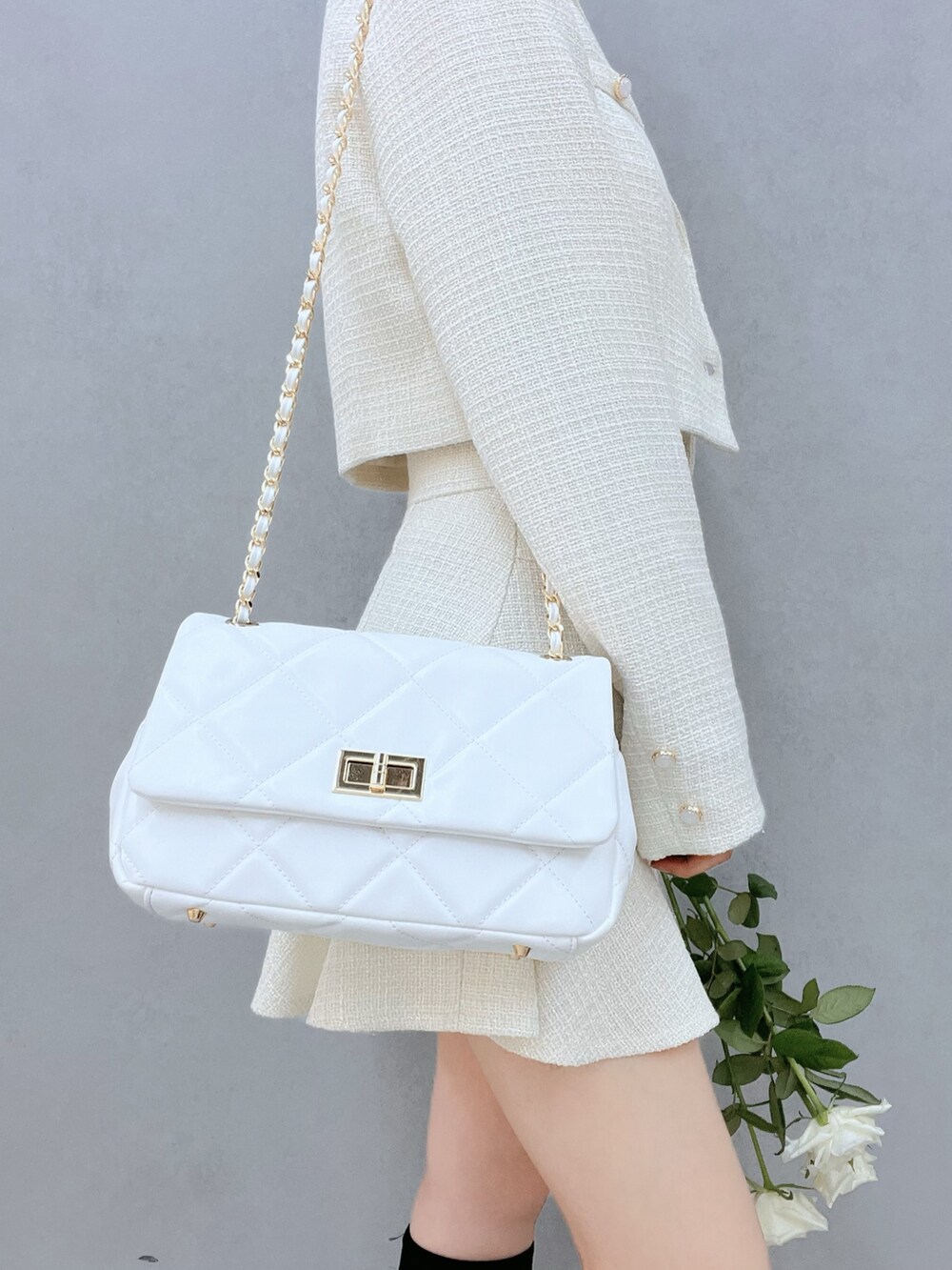 ホワイト系のテーラードジャケット、ブラック系のブーツ、ホワイト系のハンドバッグを着用したレディースの秋コーディネートの6枚目の写真