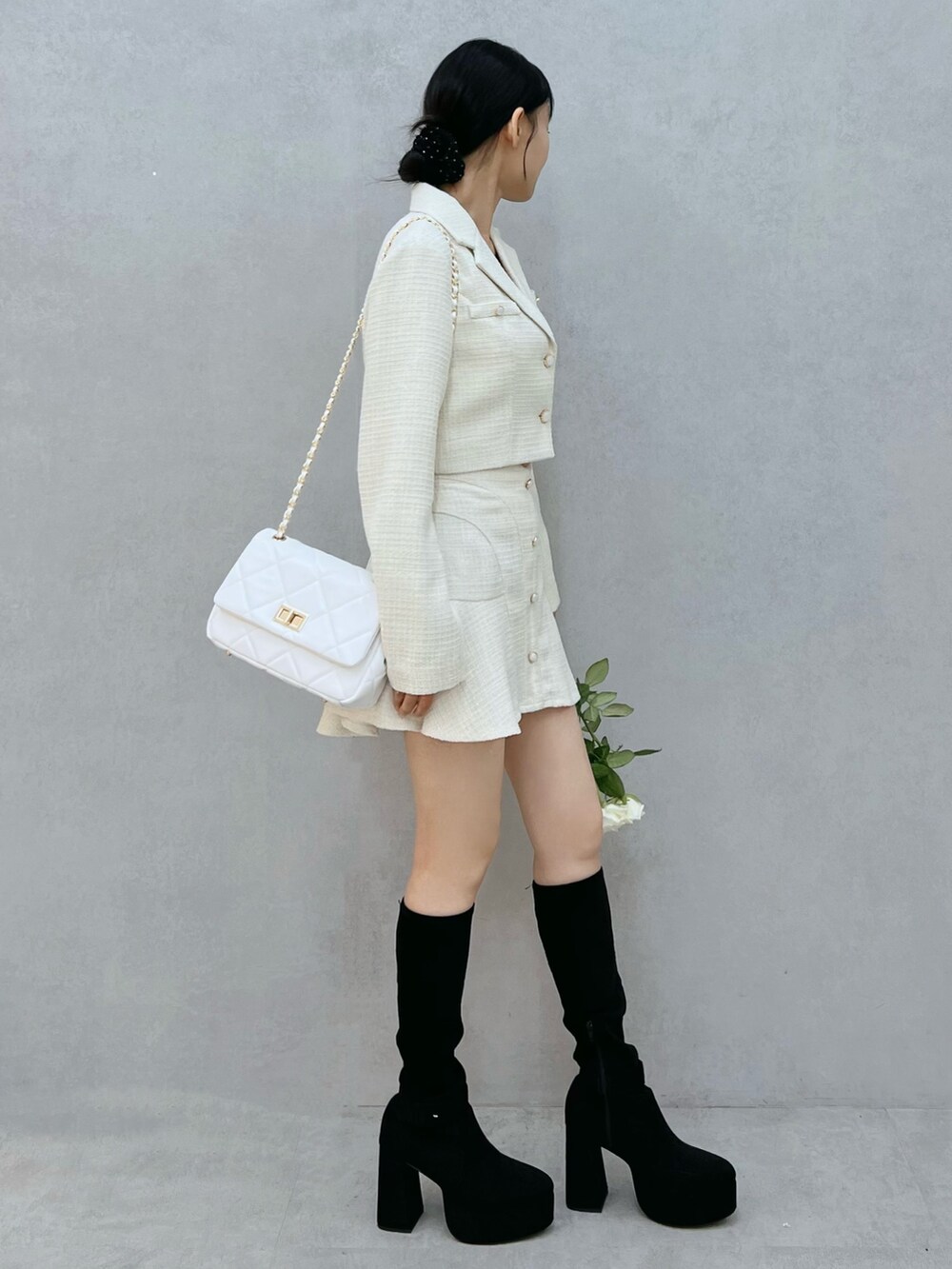 ホワイト系のテーラードジャケット、ブラック系のブーツ、ホワイト系のハンドバッグを着用したレディースの秋コーディネートの2枚目の写真