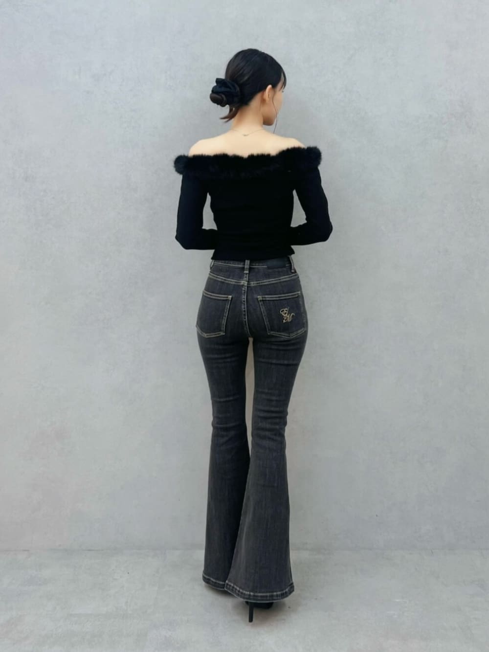 ブラック系のハンドバッグ、ブラック系のパンプス、ブラック系のデニムパンツを着用したレディースの秋コーディネートの3枚目の写真