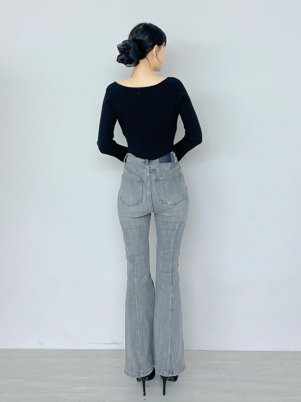 ブラック系のデニムパンツ、ブラック系のニット/セーター、ブラック系のブーツを着用したレディースの秋コーディネートの3枚目の写真