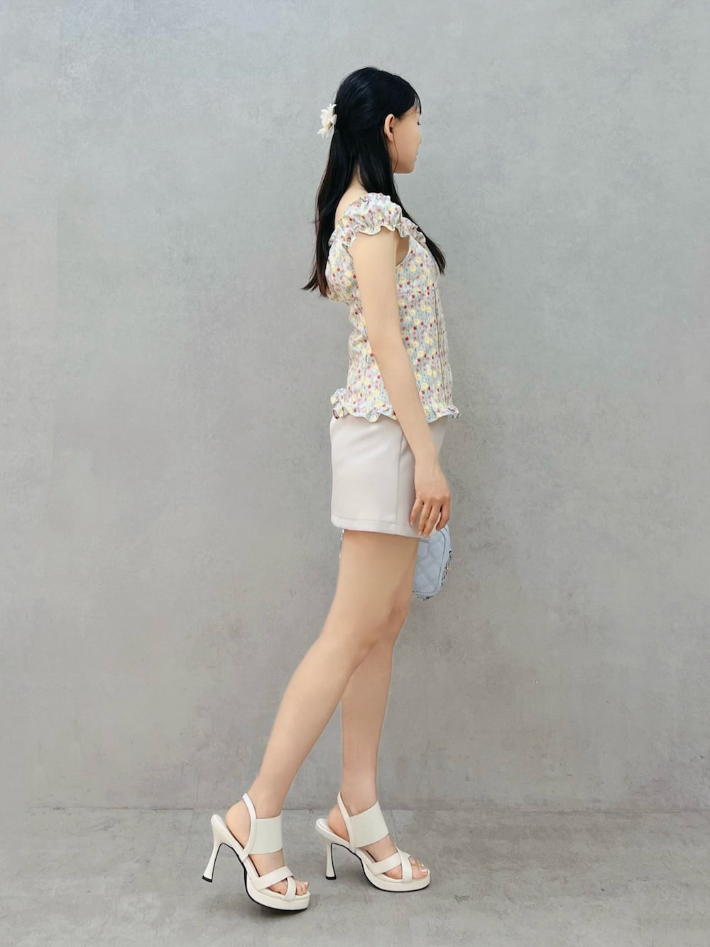 グレー系のスカート、ホワイト系のサンダル、ブルー系のシャツ/ブラウスを着用したレディースの春コーディネートの2枚目の写真