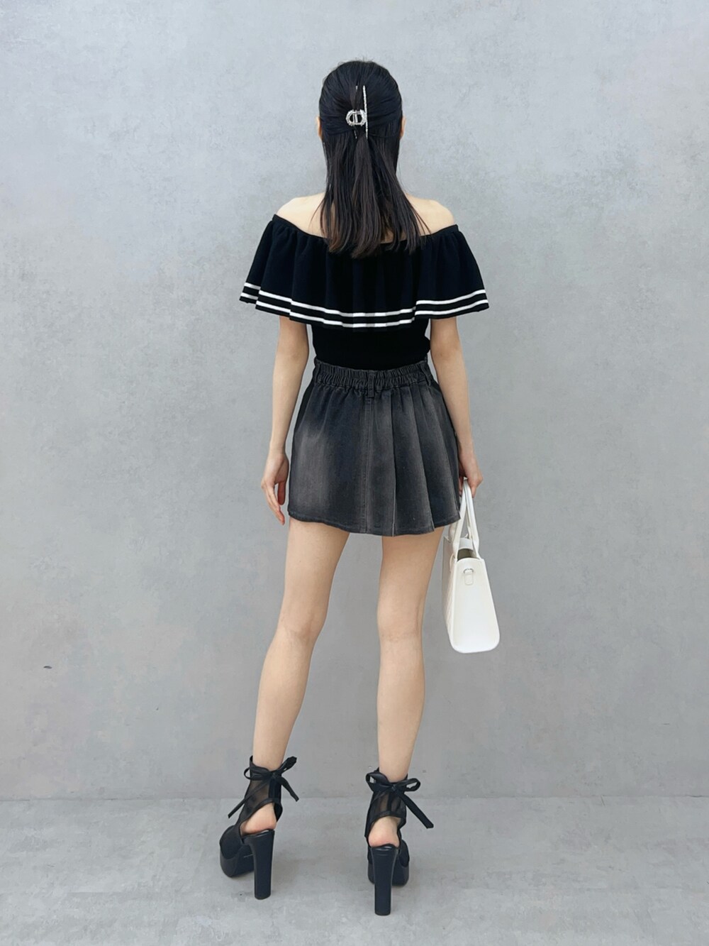 ブラック系のデニムスカート、ブラック系のサンダル、ホワイト系のハンドバッグを着用したレディースの夏コーディネートの5枚目の写真