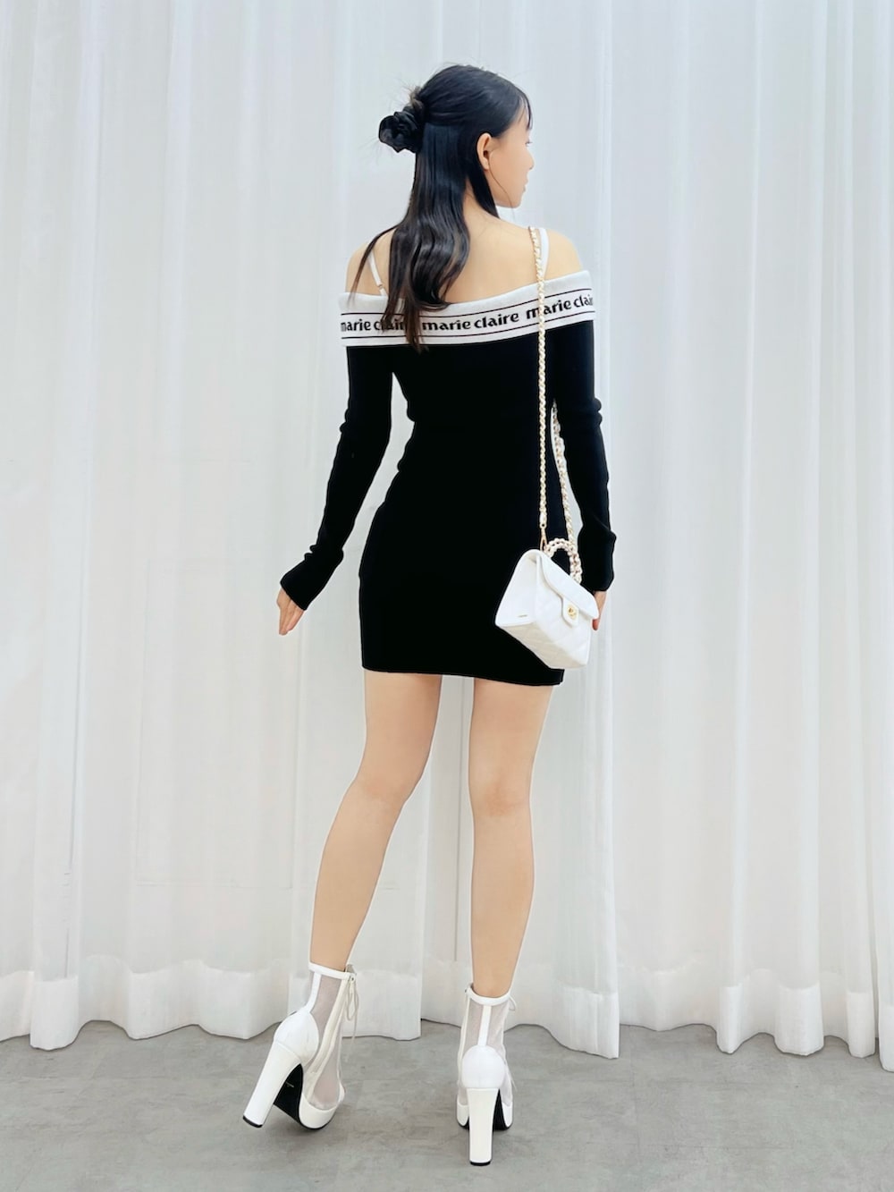 ホワイト系のブーツ、ホワイト系のハンドバッグ、ブラック系のワンピースを着用したレディースの冬コーディネートの3枚目の写真