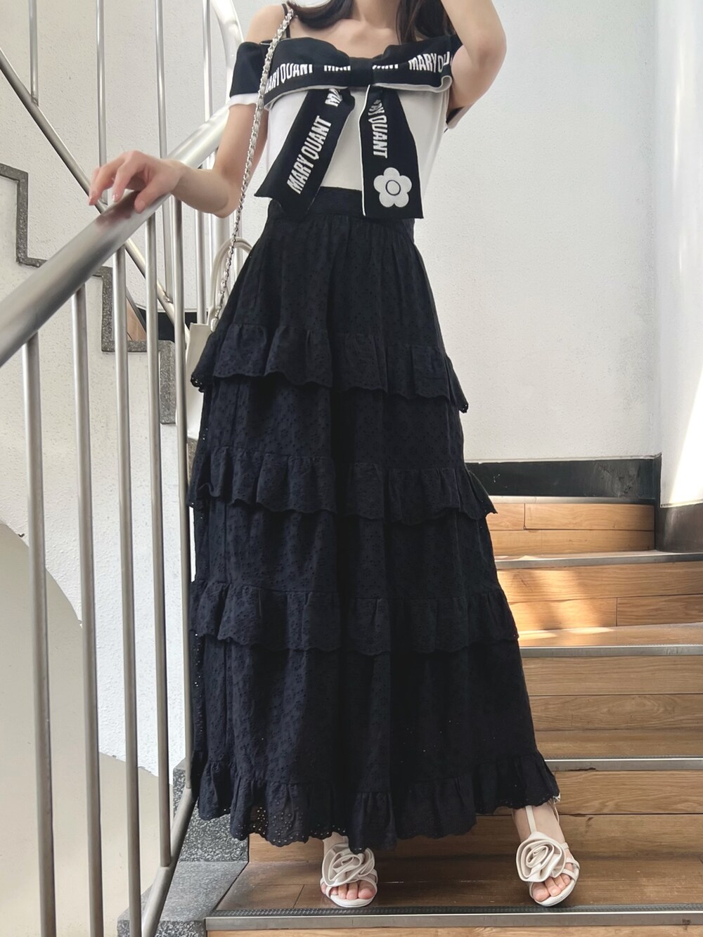 ブラック系のスカート、ホワイト系のワンピース、ホワイト系のサンダルを着用したレディースの春コーディネートの2枚目の写真