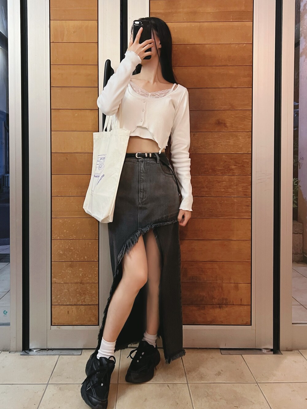 ブラック系のデニムスカート、ホワイト系のTシャツ/カットソーを着用したレディースの夏コーディネートの2枚目の写真