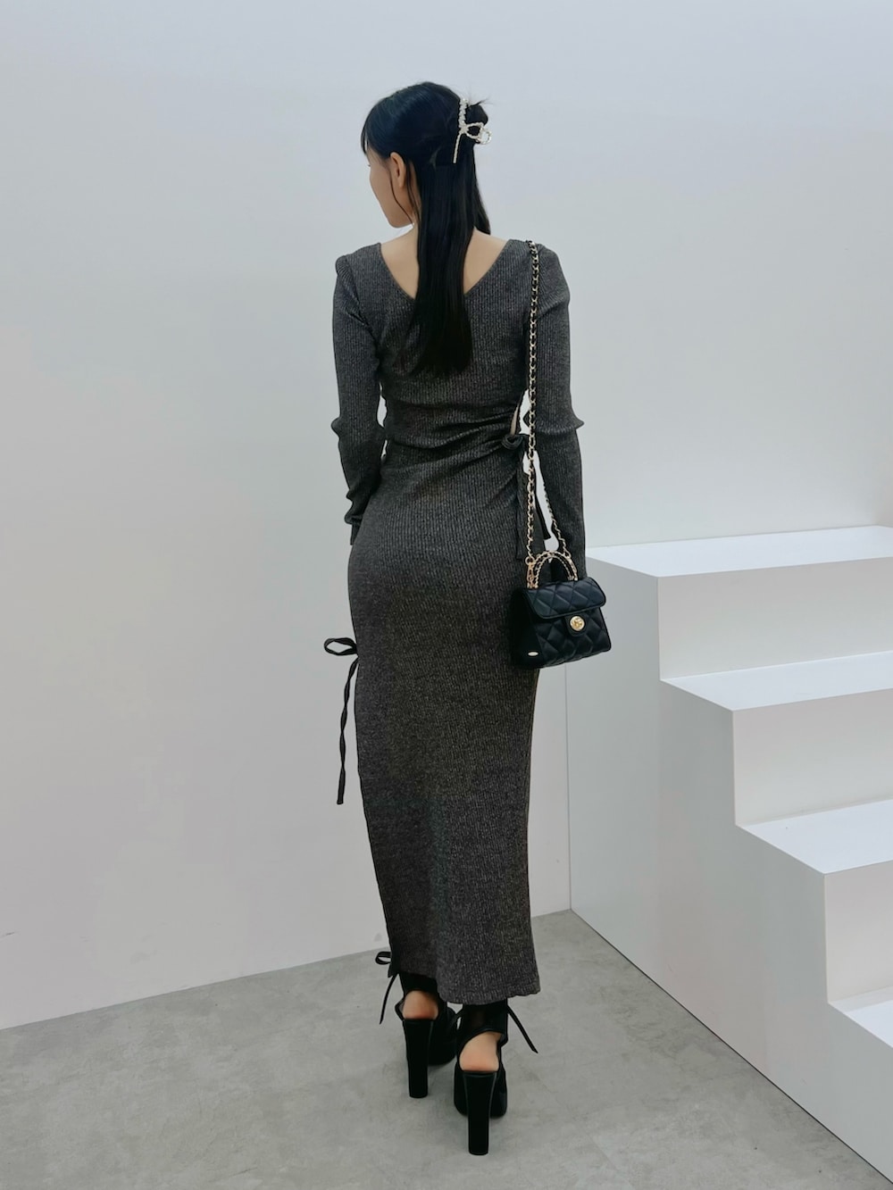 ブラック系のサンダル、グレー系のワンピース、ブラック系のハンドバッグを着用したレディースの春コーディネートの3枚目の写真