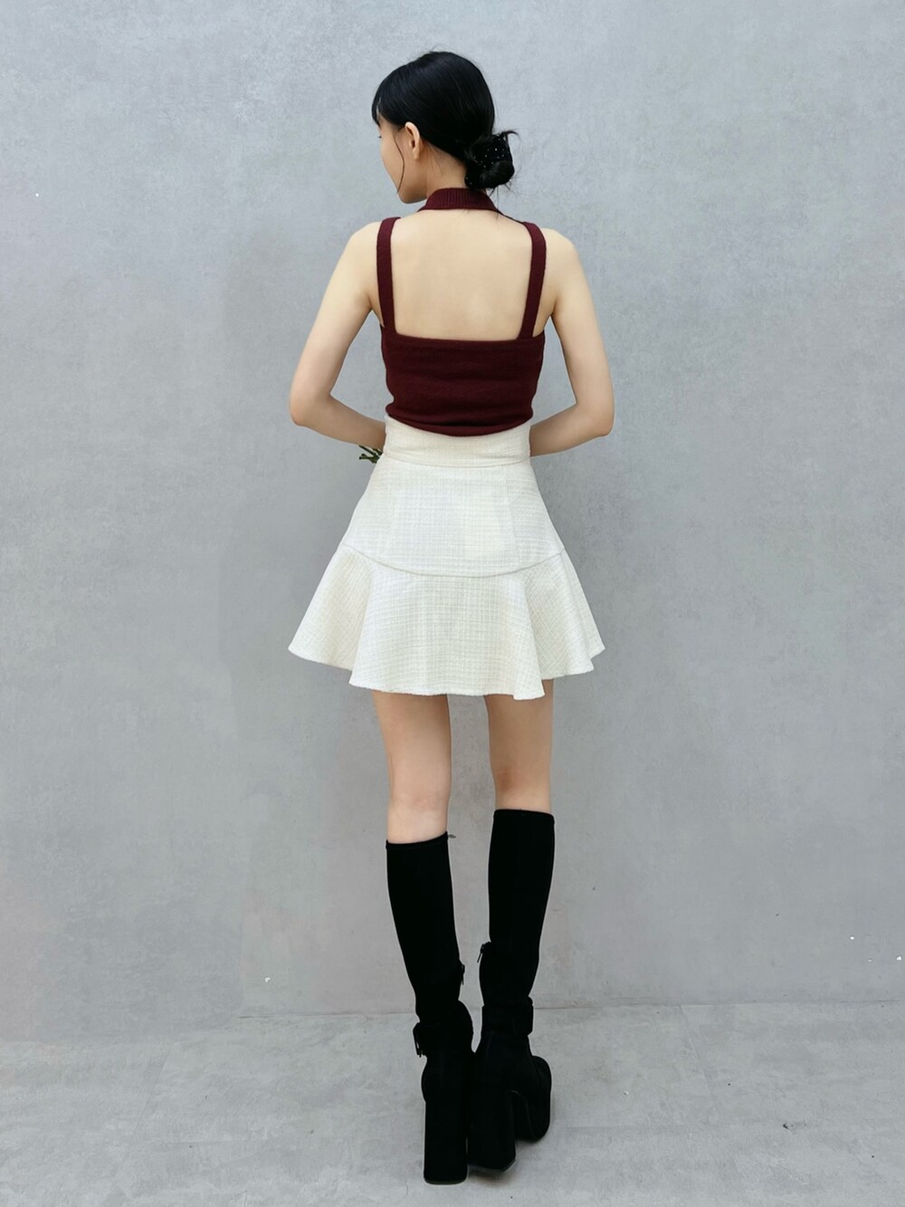 レッド系のニット/セーター、ホワイト系のスカート、ブラック系のブーツを着用したレディースの秋コーディネートの3枚目の写真