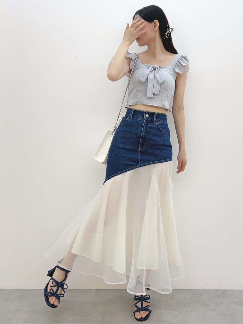 ブルー系のデニムスカート、ホワイト系のハンドバッグ、グレー系のシャツ/ブラウスを着用したレディースの春コーディネートの3枚目の写真