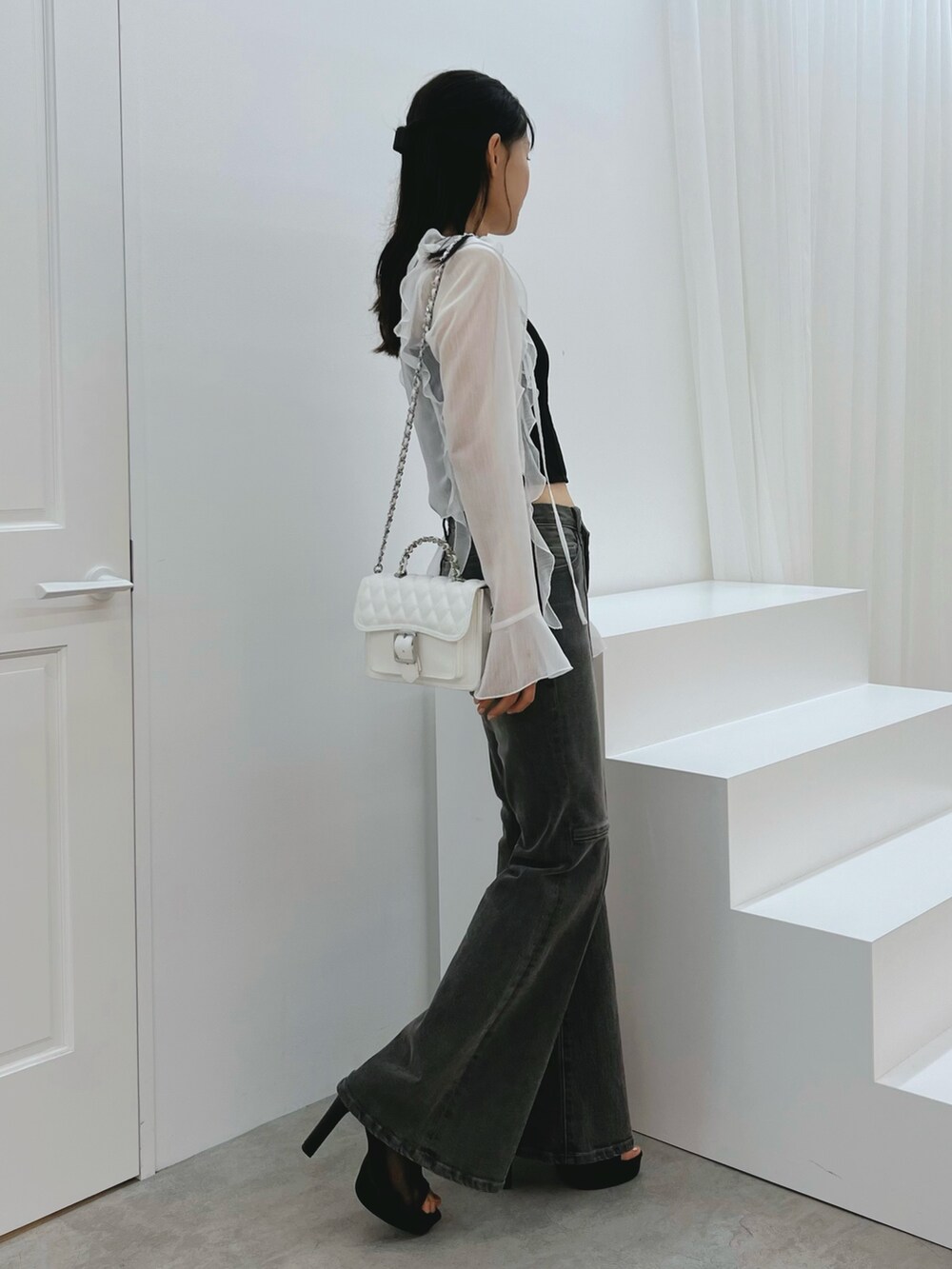 ブラック系のデニムパンツ、ブラック系のキャミソール、ホワイト系のカーディガン/ボレロを着用したレディースの秋コーディネートの2枚目の写真