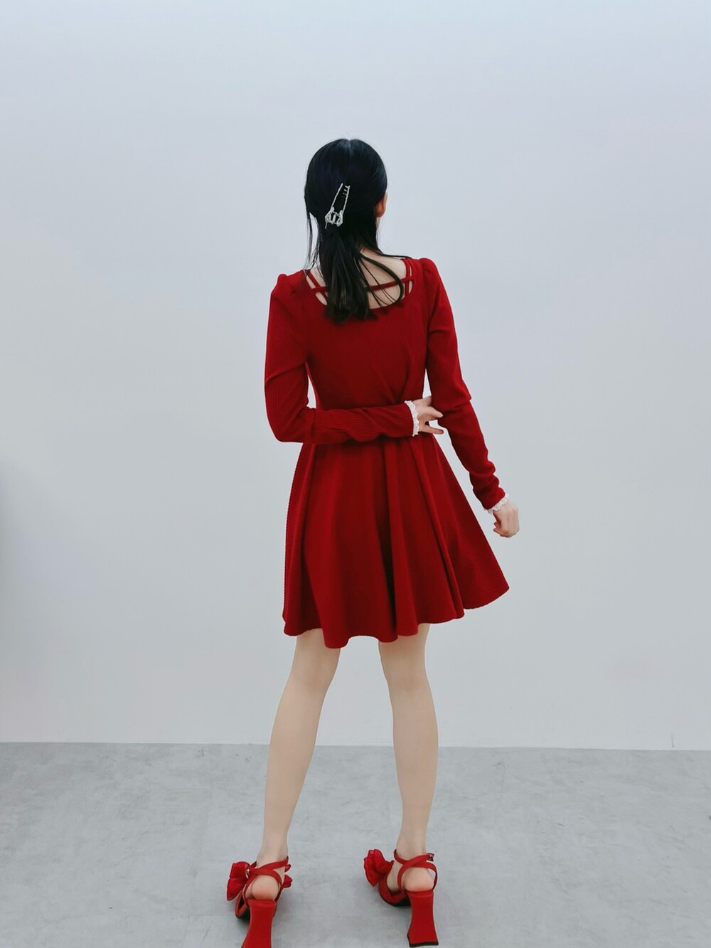 レッド系のワンピース、レッド系のパンプス、ブラック系のキャミソールを着用したレディースの冬コーディネートの4枚目の写真