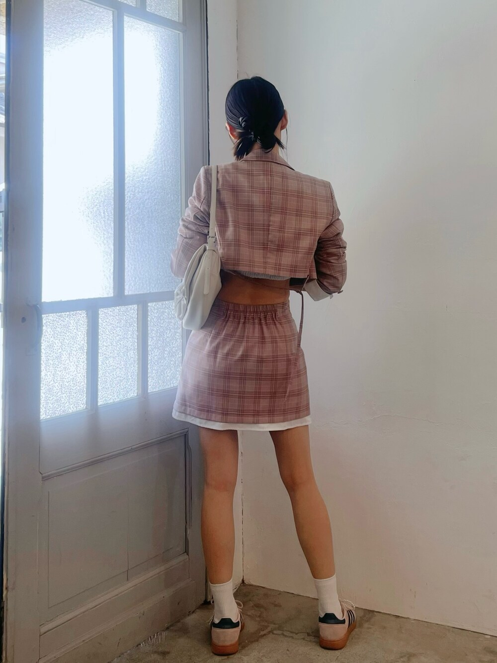 ピンク系のスカート、ホワイト系のショルダーバッグ、ピンク系のテーラードジャケットを着用したレディースの春コーディネートの6枚目の写真