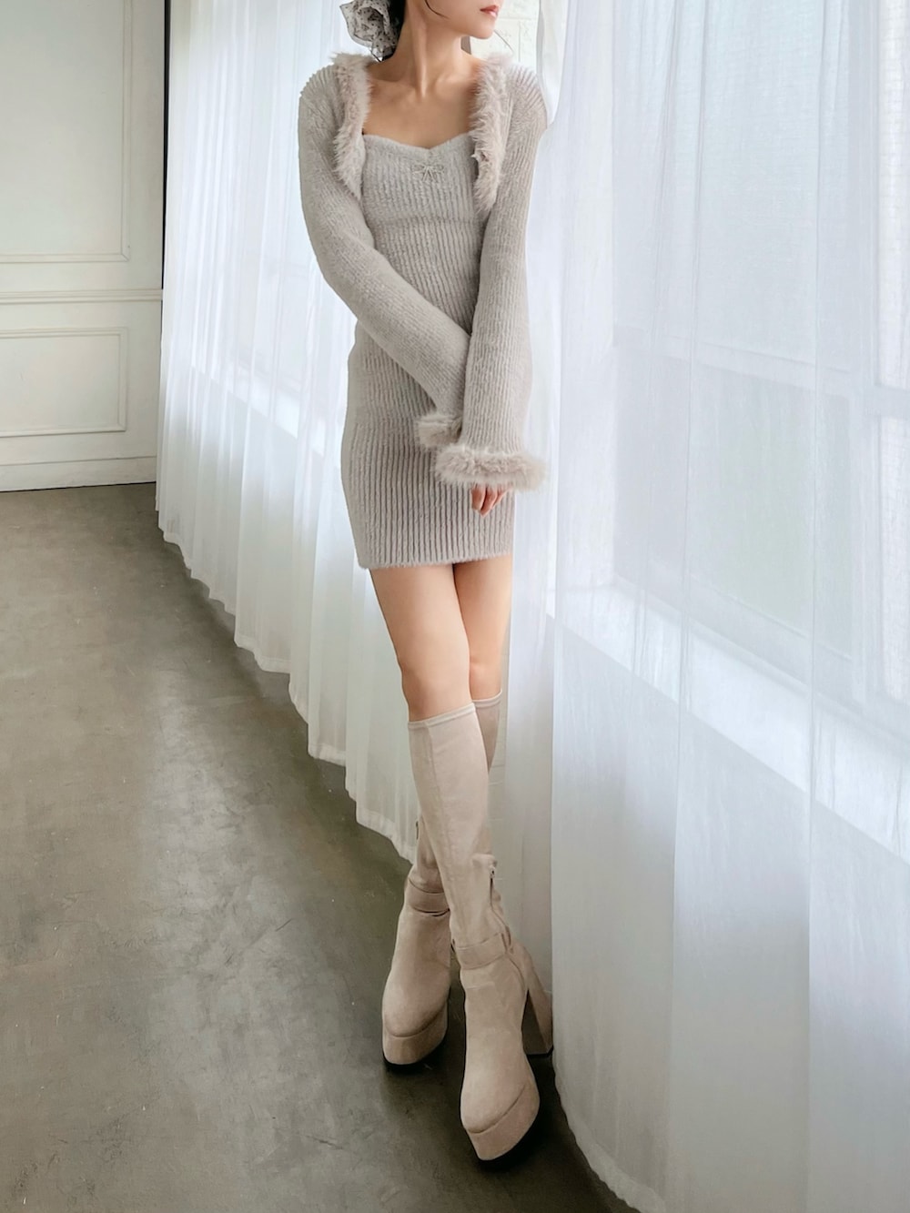 グレー系のワンピース、ホワイト系のブーツを着用したレディースの冬コーディネートの4枚目の写真