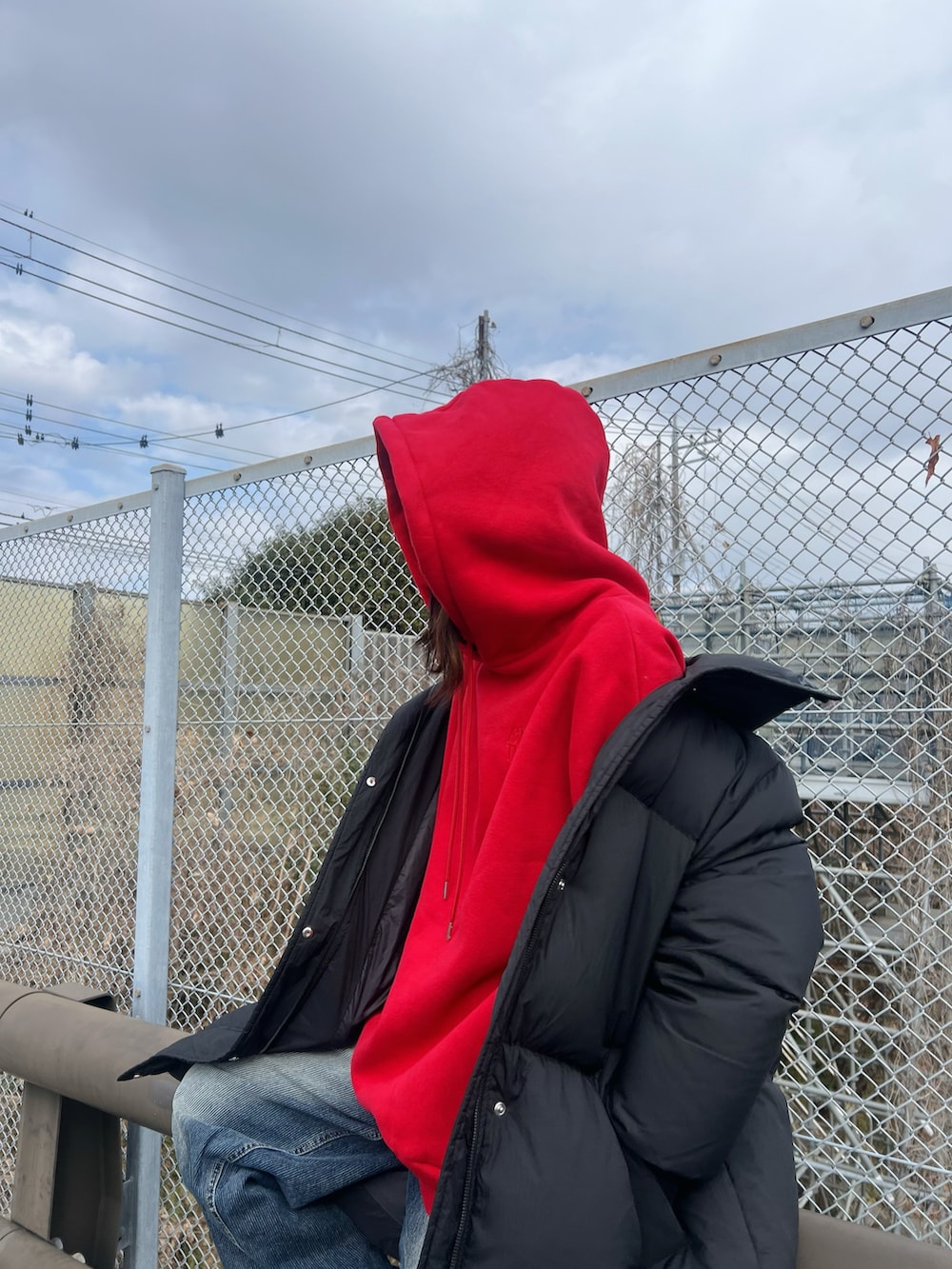 レッド系のパーカー、ブルー系のデニムパンツを着用したレディースの冬コーディネートの3枚目の写真