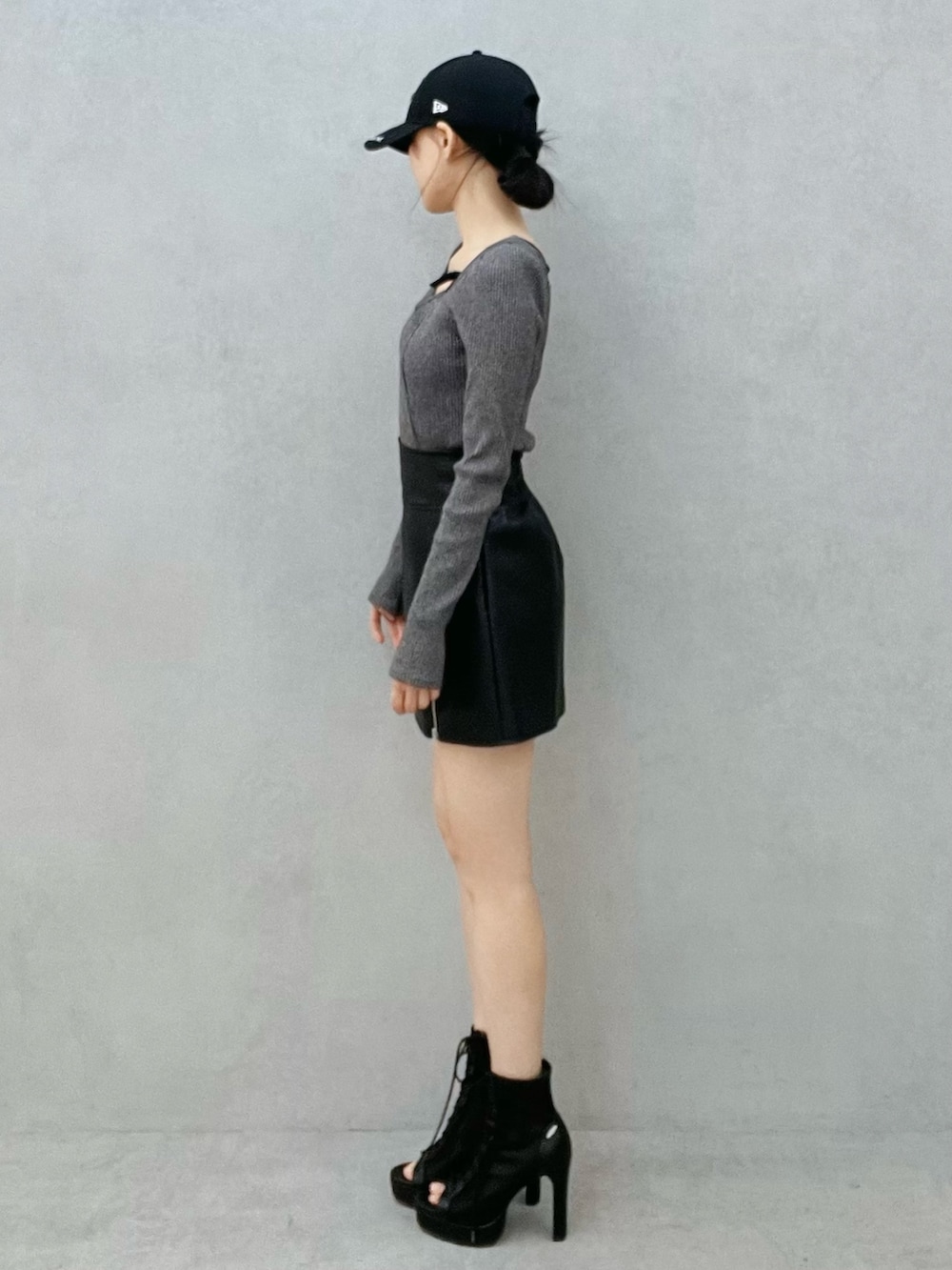 グレー系のTシャツ/カットソー、ブラック系のスカート、ブラック系のブーツを着用したレディースの冬コーディネートの2枚目の写真