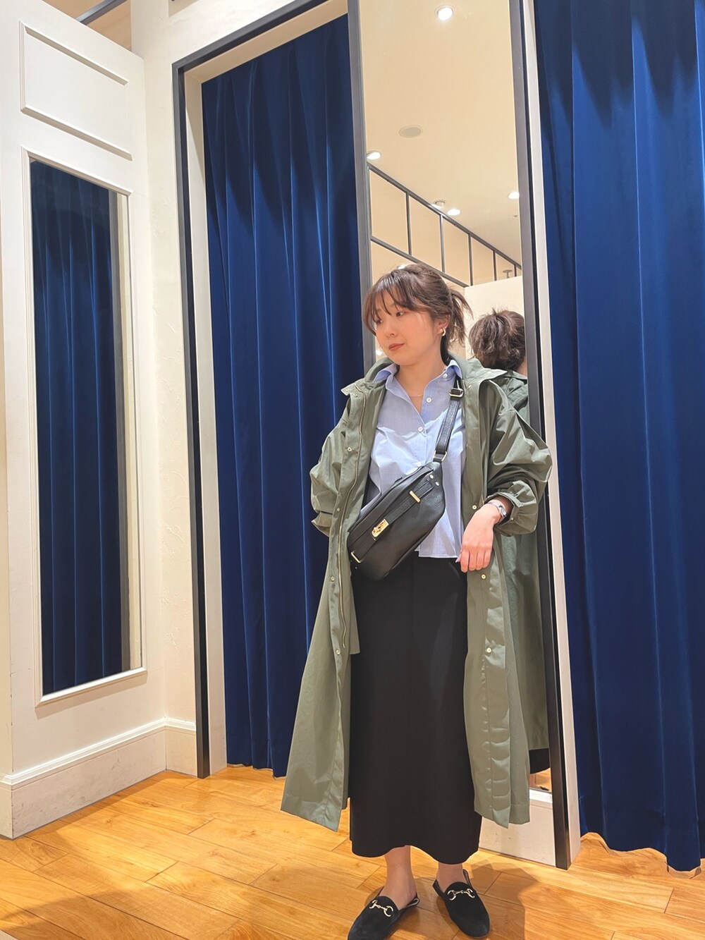 グリーン系のその他アウター、ブラック系のスカート、ブルー系のシャツ/ブラウスを着用したレディースの春コーディネートの2枚目の写真